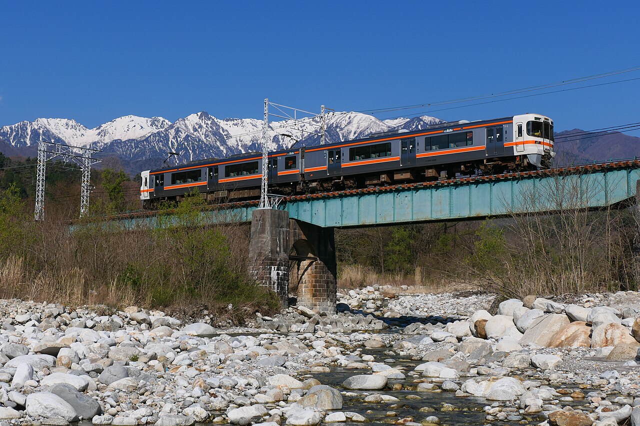 A JR Central 313-3000 series local train crossing the Nakatagiri River with the Kiso Mountains behind, on the Iida Line.