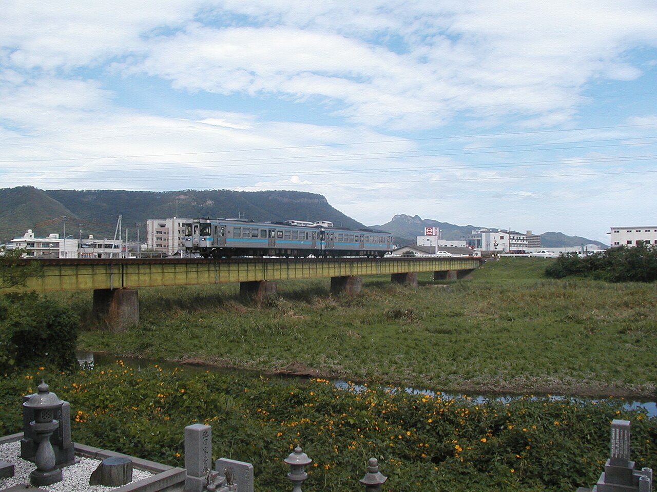 A Kōtoku Line train crossing the Kasuga River, with Yashima in the background.