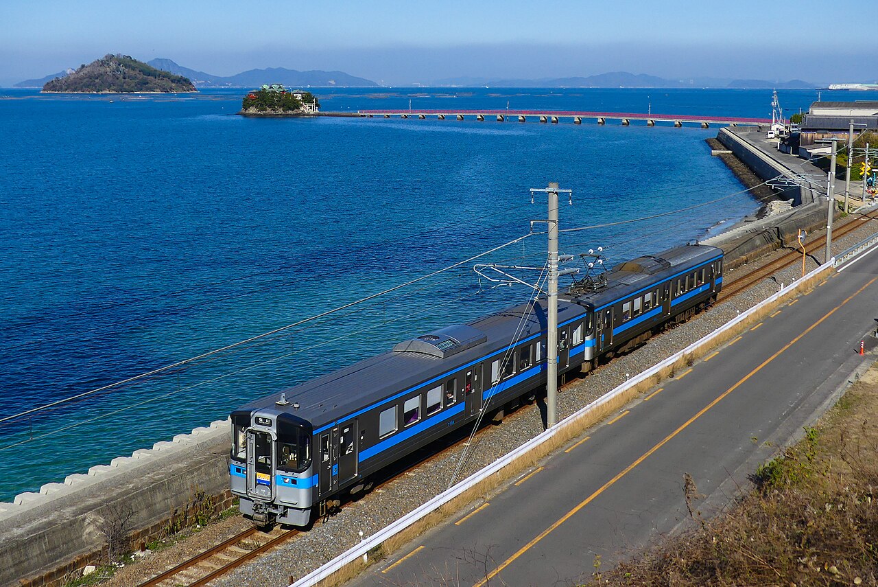 A 7000 series (7100 type) 'Sunport' rapid bound for Matsuyama running along the Seto Inland Sea on the Yosan Line.
